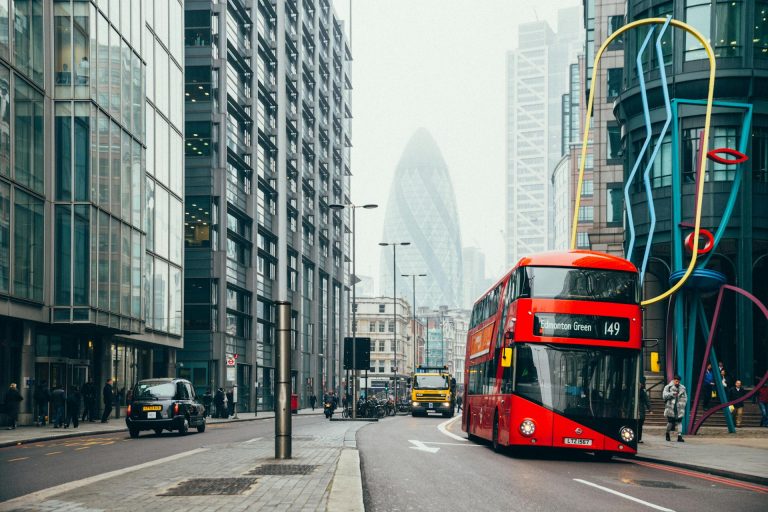 City of London scene with a red bus, black taxi cab, and the Gherkin in the background